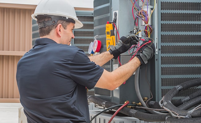 HVAC technician using diagnostic tools on residential climate-control equipment