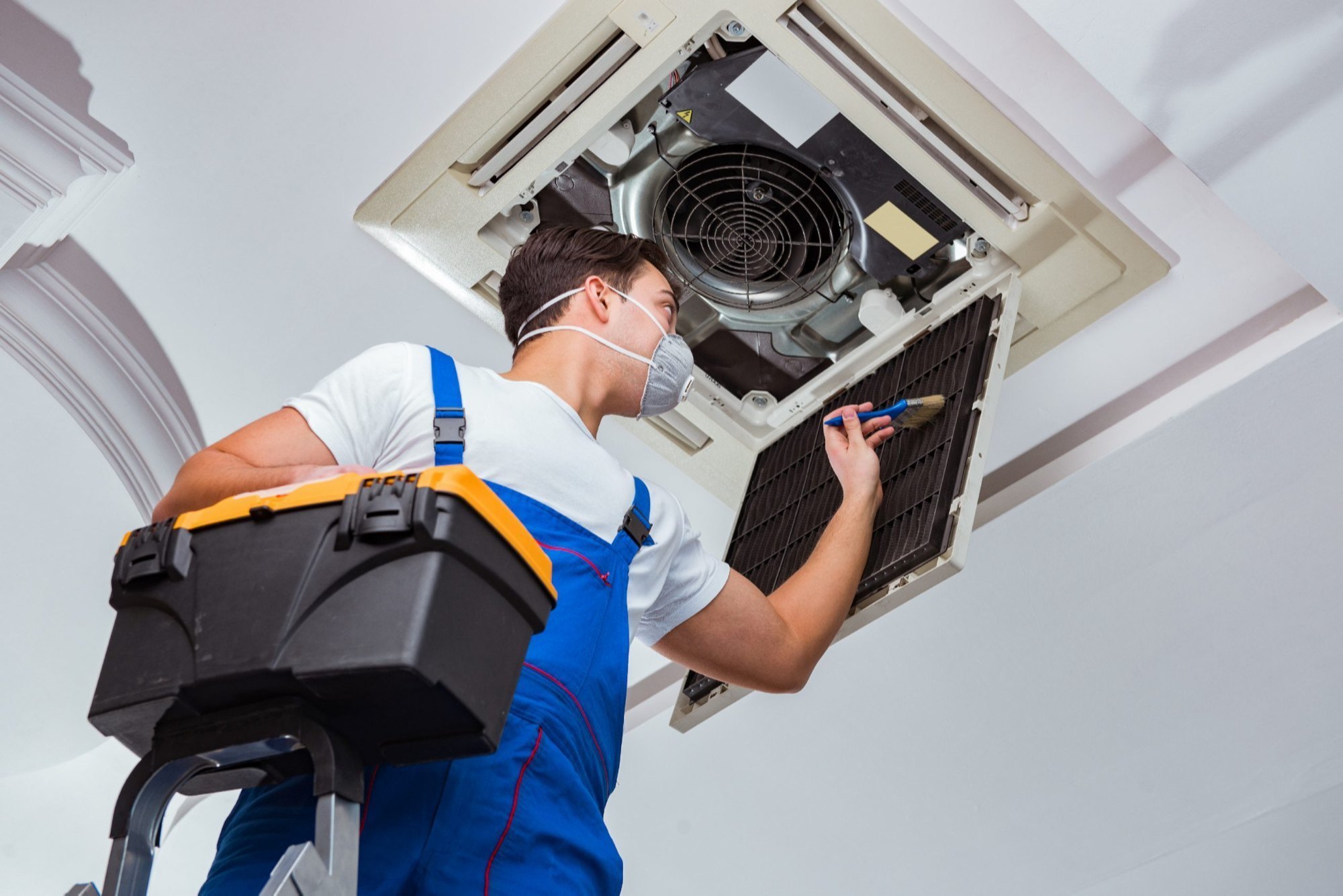 HVAC professional servicing an overhead residential ventilation unit